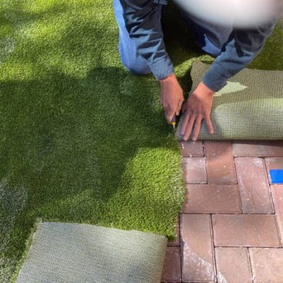 Worker installing artificial turf for dogs outside  at a residential home.